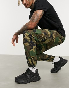 Суженные книзу брюки карго с камуфляжным принтом и фиксаторами ASOS DESIGN-Зеленый